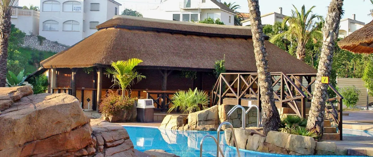 Palapa de junco africano junto a una piscina con rocas